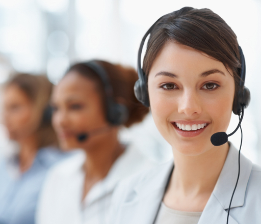 Mosolygó nő fejhallgatóval a fején, háttérben homályosan több ügyfélszolgálati munkatárs látható